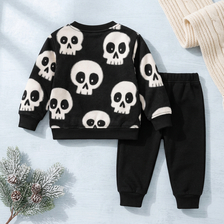 Black skull-print children's sweatshirt and black joggers on a winter-themed catalog background